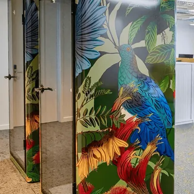 Office pod finished in a full-colour printed vinyl wrap of tropical birds and foliage, beside a glazed pod in an open-plan office