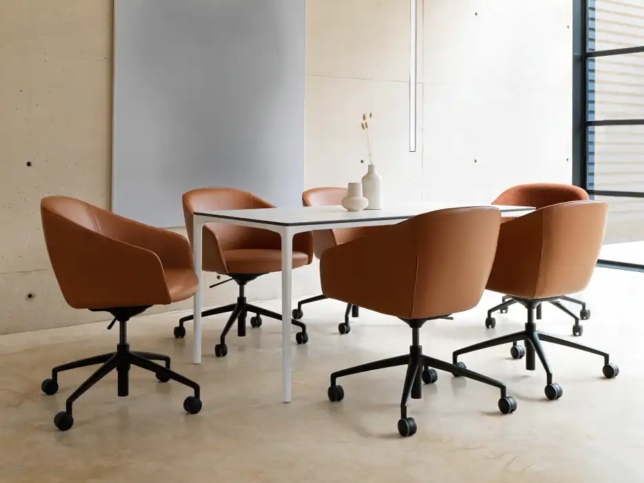 Meeting chair in a tan leather with 4 star metal bases on castors