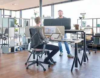 Height-adjustable office desks with black legs and dividing screens