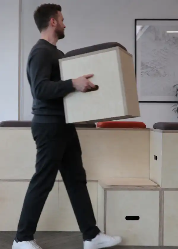 Stackable auditorium bleacher seat in plywood being carried